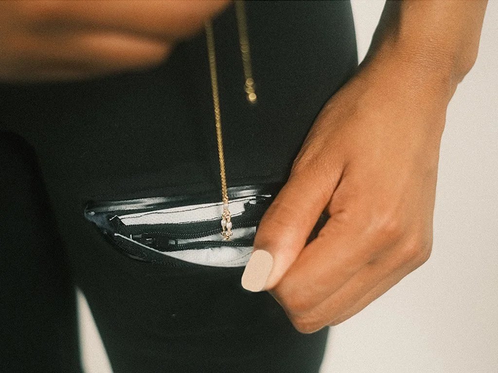 Model putting jewellery in the small SAFE pouch in the shorts pocket.
