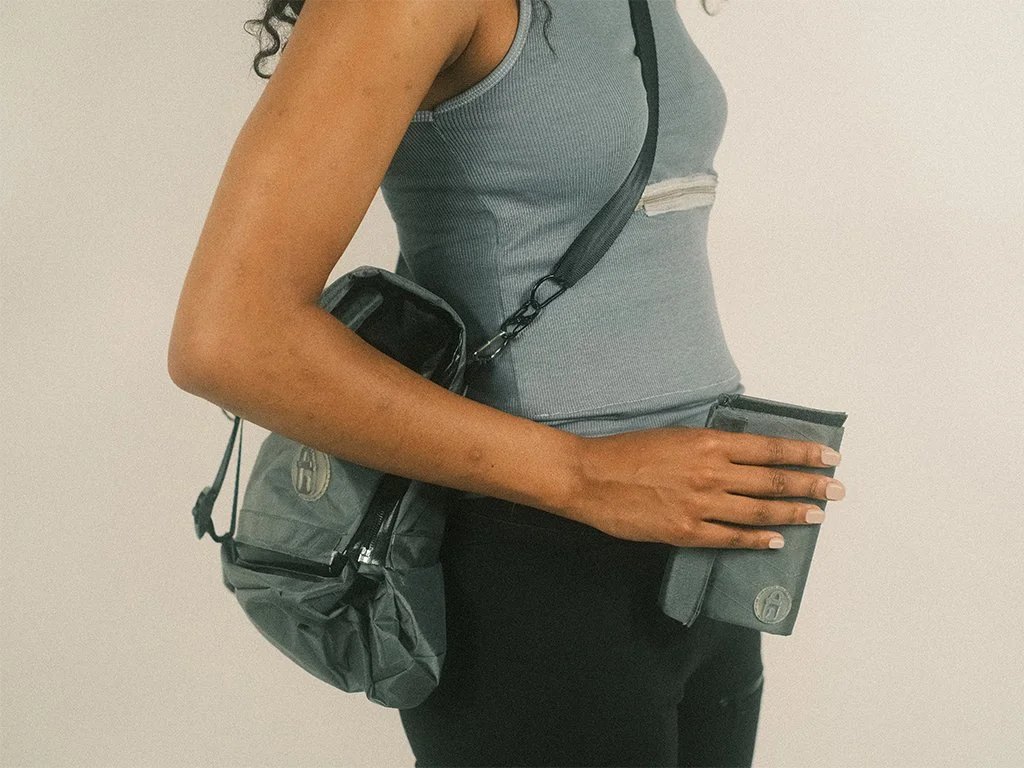 Model holding medium safe pouch with bag and wearing apparel.