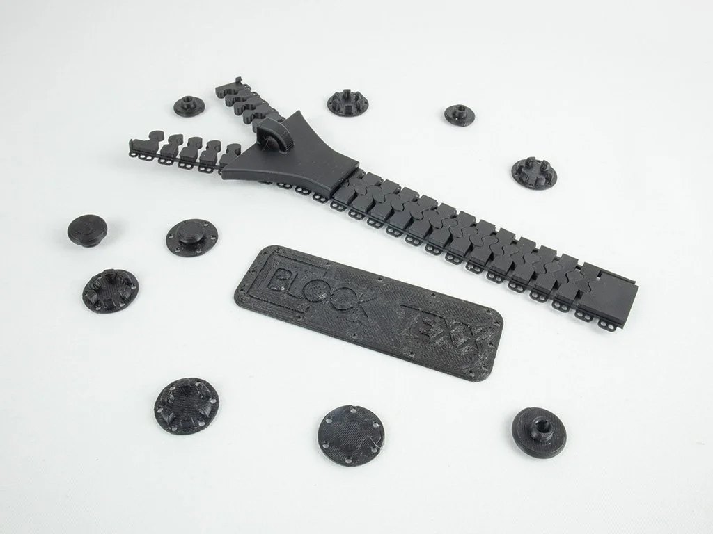 PolyTexx models PETG models of button, snap fit and zipper around a printed BlockTexx name plate made from PolyTexx material